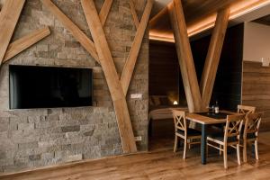 a dining room with a stone wall and a tv at Villa Greystone in Nová Lesná