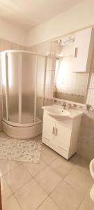 La salle de bains blanche est pourvue d'un lavabo et d'une douche. dans l'établissement Apartments Burazer, à Šibenik