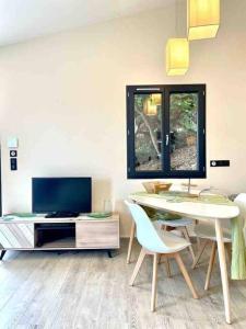 ein Wohnzimmer mit einem TV, einem Tisch und Stühlen in der Unterkunft La Maison de Katy in Le Beausset