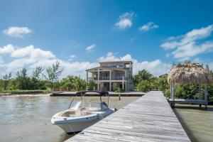 a boat docked at a dock in front of a house at Cottage 5 at Island Pearl Gold Standard Certified in Caye Caulker