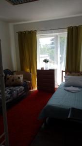 a bedroom with two beds and a window with yellow curtains at EVA HAUS in Nemėžis