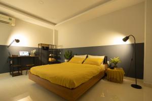 ein Schlafzimmer mit einem Bett und einem Schreibtisch mit einer Lampe in der Unterkunft Karat Home in Ho-Chi-Minh-Stadt
