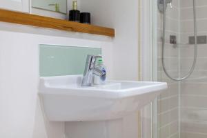W łazience znajduje się umywalka z lustrem i prysznic. w obiekcie Perfect for Long Stays Business & Family Guests! Stratford London Sleeps 6 Guests! WIFI & Netflix w Londynie