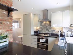 a kitchen with white cabinets and a stove top oven at Double Award Winning, Stunning 1700's Grd 2 listed cottage near Stonehenge - Elegantly Refurbished Throughout in Amesbury