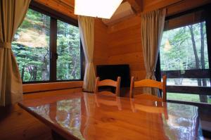 comedor con mesa, sillas y ventanas en HARUNA CABIN - Vacation STAY 62249v, en Tsumagoi