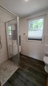 ein Bad mit einer Dusche, einem WC und einem Fenster in der Unterkunft Tornower Waldhäusl 