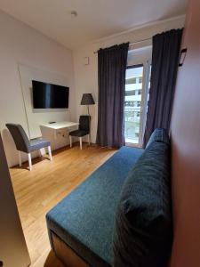 um quarto com um sofá, uma televisão e uma secretária em Messe München Smartapart em Munique