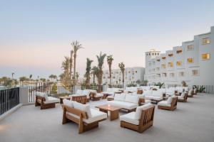 un patio con sofás blancos, mesas y palmeras en Serry Beach Resort en Hurghada