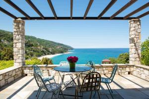 una mesa y sillas en un patio con vistas al océano en 2 beautiful sea villas 17guests, en Damouchari