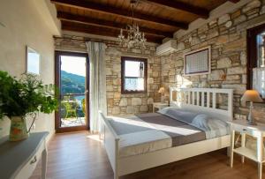 1 dormitorio con cama blanca y pared de piedra en 2 beautiful sea villas 17guests, en Damouchari