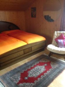 1 dormitorio con cama, alfombra y silla en Staldenried Ferienwohnung en Staldenried