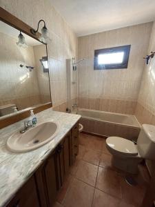 a bathroom with a sink and a toilet and a tub at Casa Rural El Escondite in Ronda