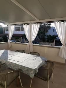 una mesa y sillas en un balcón con cortinas en villa TiCia a 100 metri dalla spiaggia con parcheggio privato, en Lido Marini