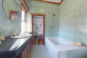a bathroom with a tub and a sink and a mirror at The French Lady Guest House - Entire House in Caye Caulker