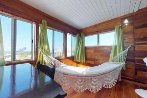 a hammock in a room with windows at The French Lady Guest House - Entire House in Caye Caulker
