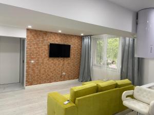 a living room with a yellow couch and a brick wall at Apart Maya in Calafat