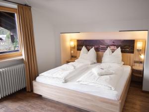 um quarto com uma cama grande com lençóis brancos e almofadas em Hotel Garni Landhaus Sonnenstern em Schönau am Königssee