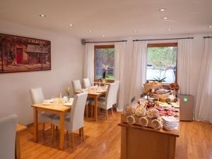 ein Esszimmer mit Tischen und Stühlen sowie einem Tisch mit Speisen in der Unterkunft Hotel Garni Landhaus Sonnenstern in Schönau am Königssee