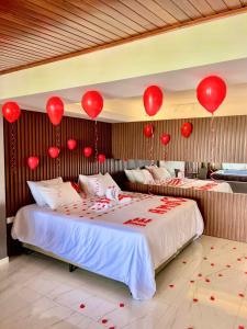 a bedroom with two beds with red balloons on the wall at Pousada Alto do Cruzeiro in Maragogi