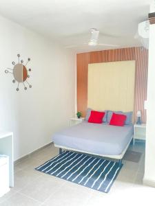 a bed with red and blue pillows in a room at Quarto Nº8 LUMA - Central Praia in Praia