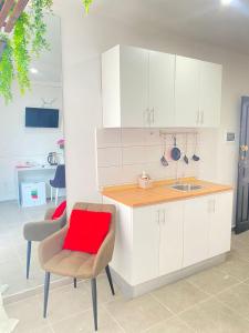 a kitchen with white cabinets and a red pillow on a chair at Quarto Nº8 LUMA - Central Praia in Praia