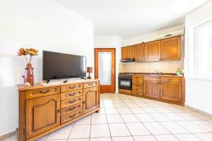 a kitchen with wooden cabinets and a flat screen tv at Ogi Seaside Gajac in Novalja