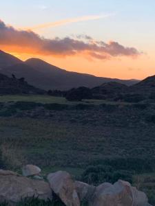 un tramonto in un campo con rocce e montagne di Villa Vigla a Zefiría