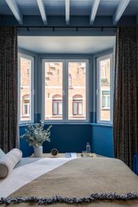 a blue bedroom with a large bed with two windows at Odit in Bruges
