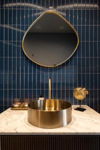 La salle de bains est pourvue d'un lavabo en or et d'un miroir. dans l'établissement Odit, à Bruges