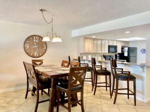 a dining room with a table and chairs and a clock at Wind Drift 102S by ALBVR - 2BR, 2BA Beautiful Upgraded Beachfront Condo near Flora Bama, Outdoor Pools and Tennis Courts in Orange Beach