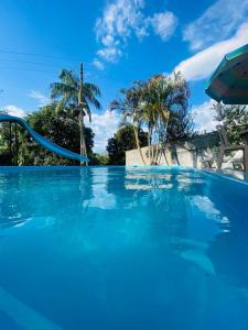 a swimming pool with blue water and palm trees at chácara solar das águas in Socorro