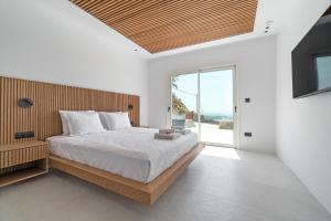 a bedroom with a large bed and a large window at Elit Villa Psarou in Psarou