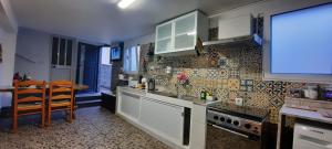 a kitchen with white cabinets and a table in it at Casa da Avó in Machico