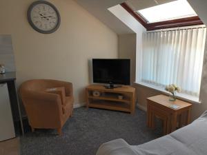 a living room with a tv and a chair and a clock at First Floor One bedroom Apartment Quiet Location in Stafford in Stafford
