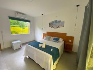 um quarto com uma cama grande com lençóis azuis e uma janela em Villa Suites Gostoso - Condomínio Beira-mar em São Miguel do Gostoso