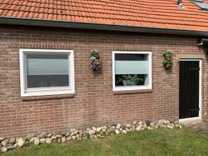 a brick house with two windows and a door at Onze boerderij in Hoogersmilde