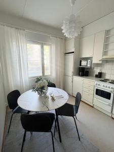 a kitchen with a white table and chairs in a room at Annalan Helmi - Viihtyisä koti hyvillä kulkuyhteyksillä ja saunalla in Tampere