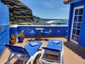 Puerto的住宿－Dachterrassenwohnung Puerto Tazacorte，阳台配有蓝色椅子和一张桌子,享有海景。