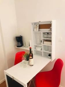 a white table with a bottle of wine and two red chairs at Apartments Endji I in Čilipi