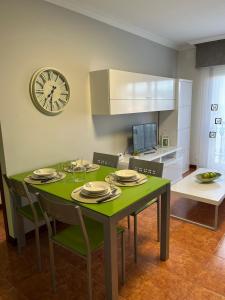 una mesa de comedor verde con sillas y un reloj en la pared en Apartamento Marichu, en Melide