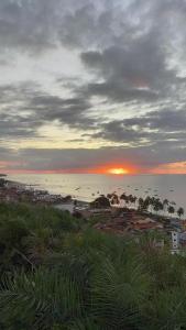 una puesta de sol sobre una playa con una ciudad y el océano en Pousada Alto do Cruzeiro, en Maragogi