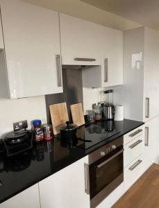 a kitchen with white cabinets and a black counter top at 1 bedroom apartment in London