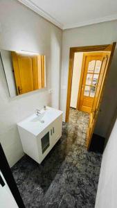 La salle de bains est pourvue d'un lavabo blanc et d'un miroir. dans l'établissement Playa Bonita Apartment, à Puerto de Sagunto