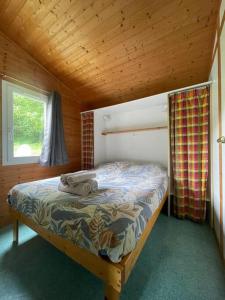 a bedroom with a bed in a cabin with a window at Chalet au bord de l'étang in Sérilhac