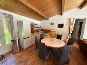 La cuisine est équipée d'une table, de chaises et d'un réfrigérateur. dans l'établissement Maison indépendante avec piscine, à Jaujac