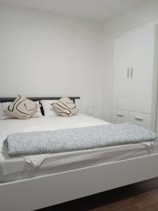 a white bedroom with a large white bed at Studio appMZ in Krk