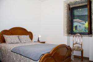 ein Schlafzimmer mit einem Bett, einem Fenster und einem Stuhl in der Unterkunft Quinta do Bairro in Vieira do Minho