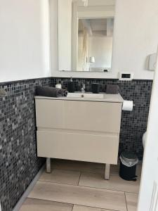 bagno con lavandino bianco e specchio di Appartamento confortevole a Cagliari