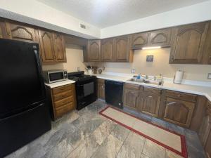 a kitchen with wooden cabinets and a black refrigerator at Scottish Inns Motel - Osage Beach in Osage Beach