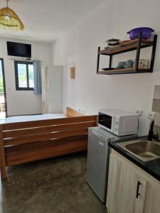 een keuken met een magnetron en een bed erin bij Hôtel de la plage in Ambatoloaka